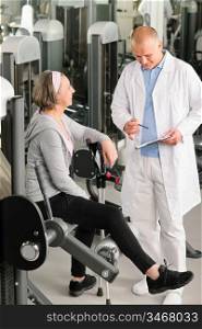 Physical therapist male assist active senior woman exercise at gym