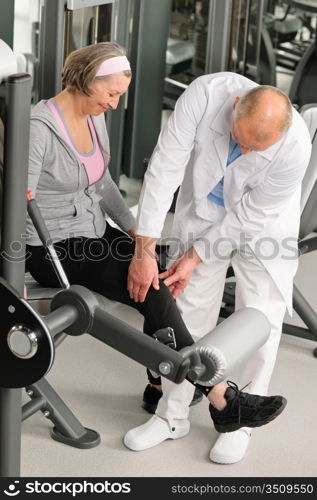 Physical therapist male assist active senior woman exercise at gym