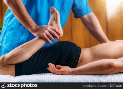 Physical therapist massaging injured leg of a male athlete. Sports injury physical therapy treatment.. Legs Sports Massage Physical Therapy