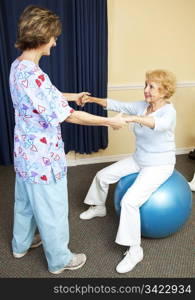 Physical therapist using pilates ball to work with senior chiropractic patient.