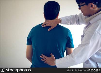 Physical therapists are using hands to check the back of the patient.