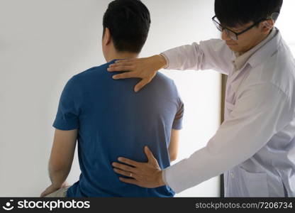 Physical therapists are using hands to check the back of the patient.