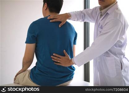 Physical therapists are using hands to check the back of the patient.