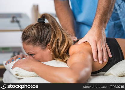 Physical therapy. Therapist applying strong pressure to shoulder muscles