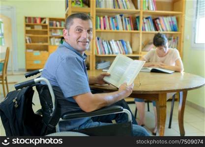 physically handicapped man with books in wheelchair
