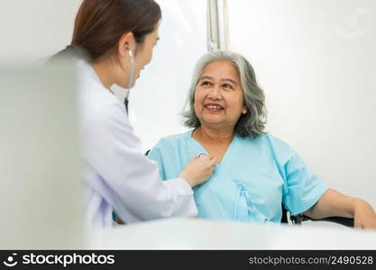 Physician examining heart with a stethoscope and talking with a senior woman at a clinic for check yearly checkup, Medicine health care service and medical insurance concept.