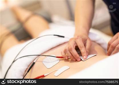 Physiotherapist applying electro stimulation in physical therapy to a young woman.. Electro stimulation in physical therapy to a young woman