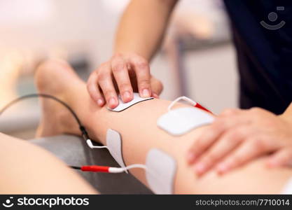 Physiotherapist applying electro stimulation in physical therapy to a young woman.. Electro stimulation in physical therapy to a young woman