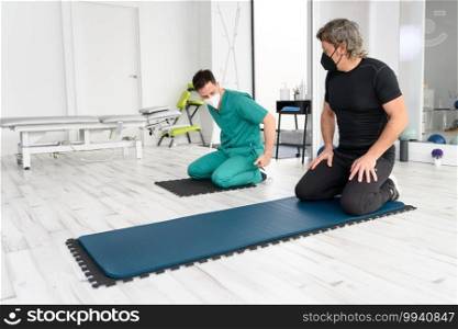 Physiotherapist assisting man in performing exercise on mat. High quality photo. Physiotherapist assisting man in performing exercise on mat