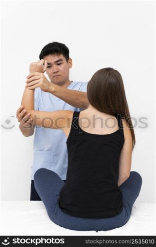 physiotherapist doing elbow exercises with female patient