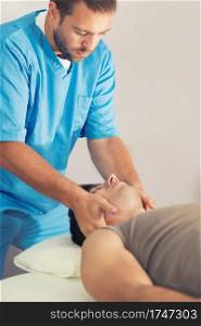 Physiotherapist doing healing treatment on man&rsquo;s neck, Therapist wearing blue uniform, Osteopath, Chiropractic adjustment, patient lying on massage table
