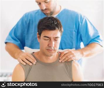 Physiotherapist doing healing treatment on man’s shoulders and neck, Therapist wearing blue uniform, Osteopath,  Chiropractic adjustment, pain relief concept