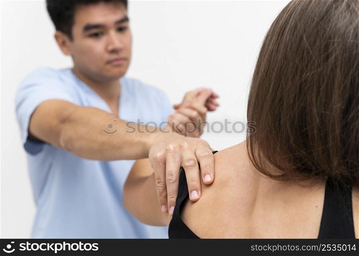physiotherapist doing shoulder exercises with female patient