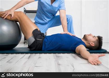 Physiotherapist helps handsome young patient with pilates exercises. High quality photo. Physiotherapist helps handsome young patient with pilates exercises.