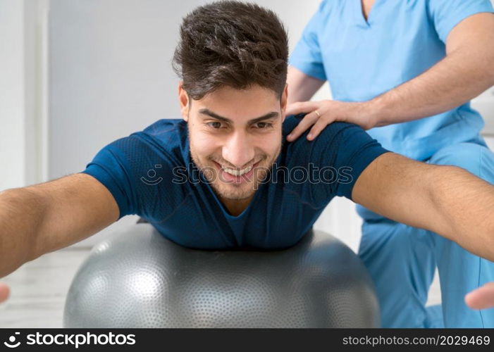 Physiotherapist helps handsome young patient with pilates exercises. High quality photo. Physiotherapist helps handsome young patient with pilates exercises.