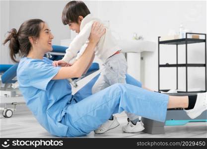 Physiotherapist hugging a little boy with a disability at rehabilitation clinic. Kid with cerebral palsy laughing and having fun. High quality photo. Physiotherapist hugging a little boy with a disability at rehabilitation clinic. Kid with cerebral palsy laughing and having fun.