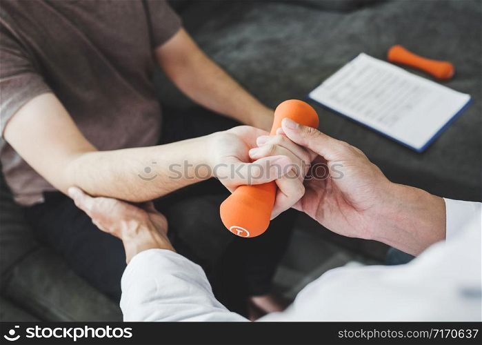 Physiotherapist man giving exercise with dumbbell treatment About Arm and Shoulder of athlete male patient Physical therapy Visit the patient&rsquo;s home