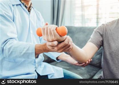 Physiotherapist man giving exercise with dumbbell treatment About Arm and Shoulder of athlete male patient Physical therapy Visit the patient&rsquo;s home