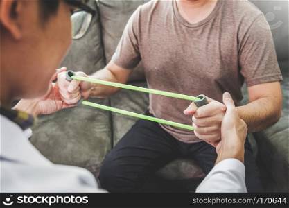 Physiotherapist man giving resistance band exercise treatment About Chest muscles and Shoulder of athlete male patient Physical therapy Visit the patient&rsquo;s home