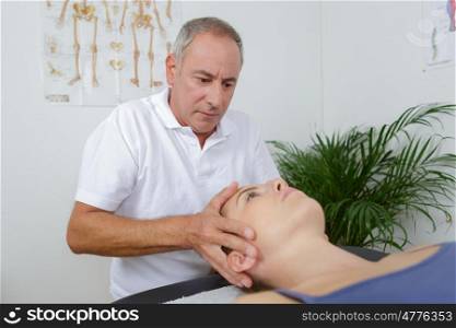 physiotherapist massages holding male clients head