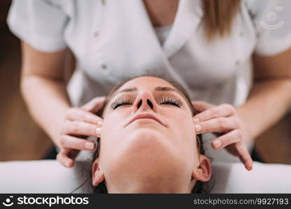 Physiotherapist massaging female patient head. Head Sports Massage Therapy
