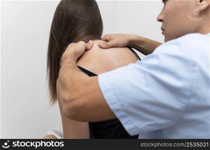 physiotherapist massaging female patient s upper back
