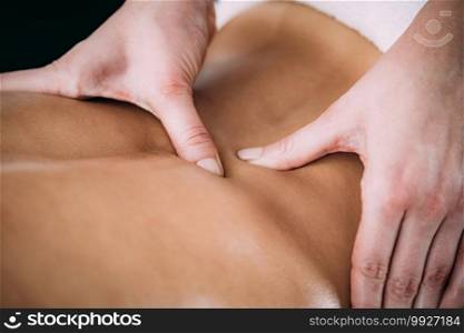 Physiotherapist massaging female patient with injured back muscle. Sports injury treatment.. Back Sports Massage Therapy