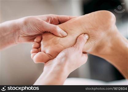 Physiotherapist massaging female patient with injured foot. Sports injury treatment.. Foot Sports Massage Therapy