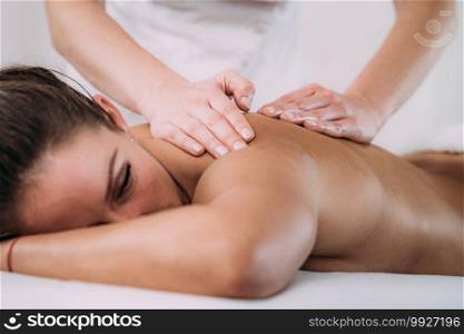 Physiotherapist massaging female patient with injured lower back muscle. Sports injury treatment.. Back Sports Massage Therapy