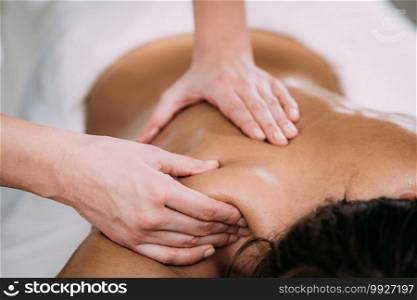 Physiotherapist massaging female patient with injured shoulder blade.  Sports injury treatment.. Shoulder blade Sports Massage Therapy