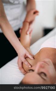 Physiotherapist massaging female patient with injured shoulder.  Sports injury treatment.. Shoulder Sports Massage Therapy
