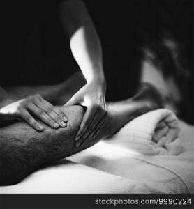 Physiotherapist massaging male patient with injured leg - calf muscle. Sports injury treatment.