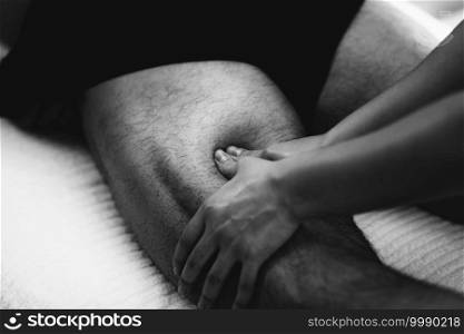 Physiotherapist massaging male patient with injured leg muscle. Sports injury treatment.