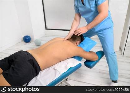 Physiotherapist massaging the back of a young athlete in the sports rehabilitation clinic. High quality photo .. Physiotherapist massaging the back of a young athlete in the sports rehabilitation clinic.