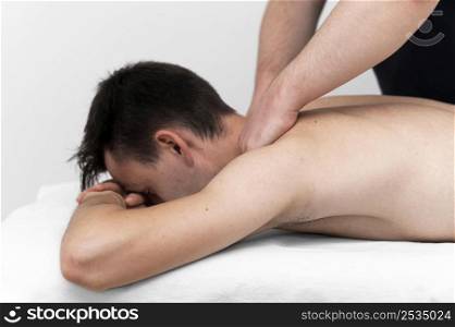 physiotherapist performing back massage male patient