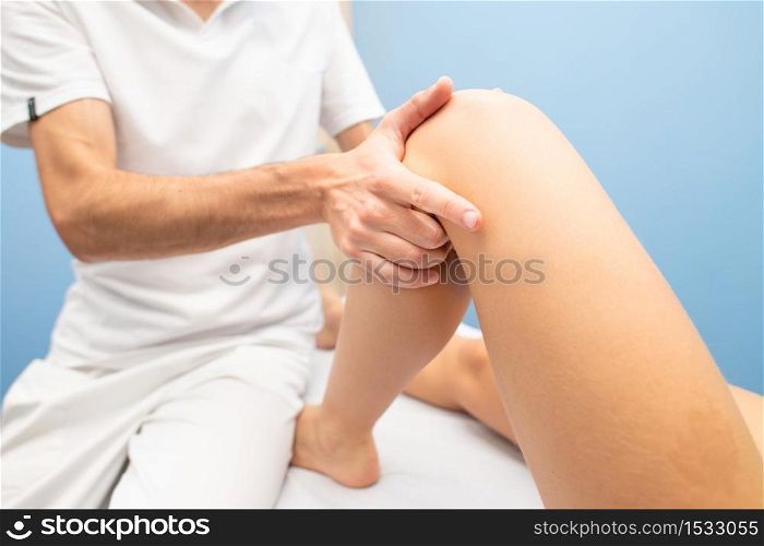 Physiotherapist performs knee drawer test to a woman.