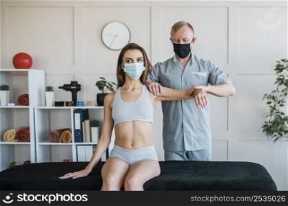 physiotherapist wearing medical mask during therapy session with woman