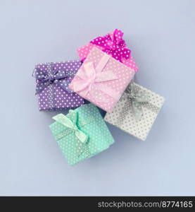 Pi≤of a small colored gift boxes with ribbons lies on a vio≤t background. Minimalism flat lay top view.. Pi≤of a small colored gift boxes with ribbons lies on a vio≤t background