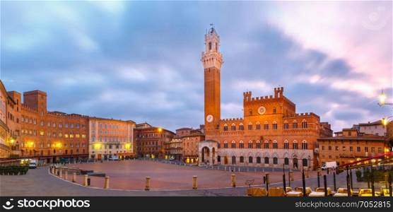Piazza del Campo at beautiful sunrise, Siena Italy. Mangia Tower or Torre del Mangia towering above of the Palazzo Pubblico on Piazza del Campo in medieval city of Siena at beautiful sunrise, Tuscany, Italy