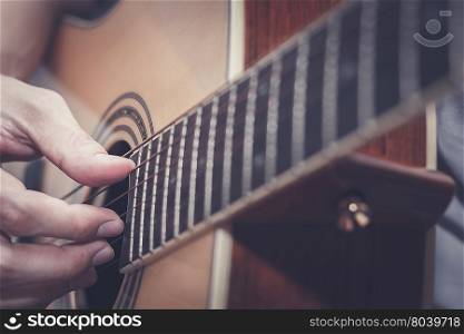 Picking acoustic guitar with shallow depth of field