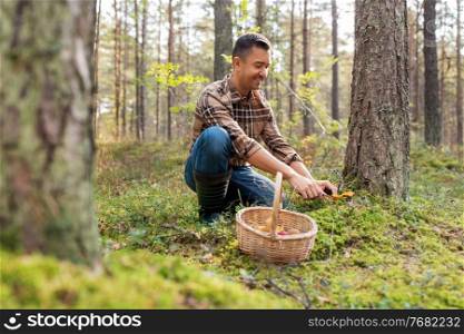 picking season and leisure people concept - happy smiling middle aged man with wicker basket of mushrooms in autumn forest. happy man with basket picking mushrooms in forest