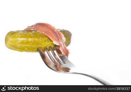 Pickle with anchovies on a fork with white background