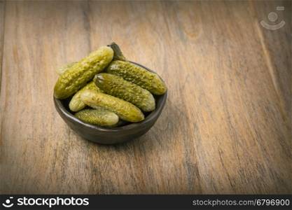 Pickled cucumbers in a wooden bowl&#xA; against dark rustic background