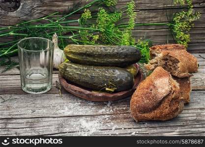 pickled cucumbers. Pickled cucumbers with dill and vodka shot glass on wooden background in country style.Photo tinted.
