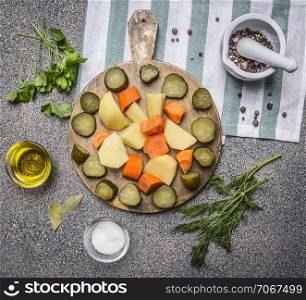 pickled cucumbers, potatoes, carrots and seasoning with herbs on wooden rustic background top view close up