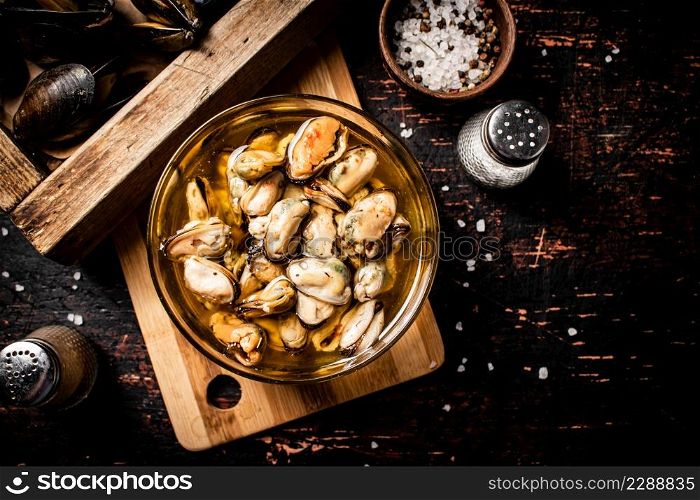 Pickled mussels in a bowl. Against a dark background. Top view. High quality photo. Pickled mussels in a bowl.
