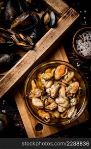 Pickled mussels in a bowl. Against a dark background. Top view. High quality photo. Pickled mussels in a bowl.