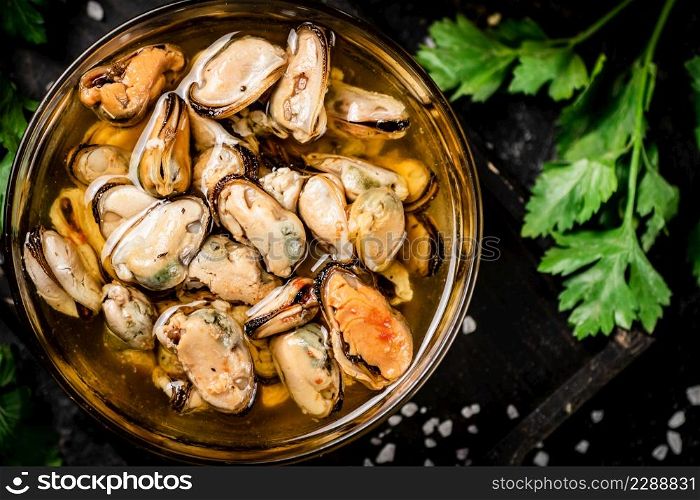 Pickled mussels in a bowl with parsley. On a black background. High quality photo. Pickled mussels in a bowl with parsley.