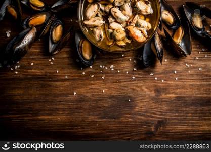 Pickled mussels in a glass bowl. On a wooden background. High quality photo. Pickled mussels in a glass bowl.