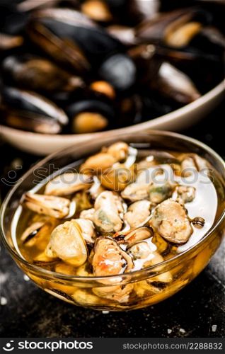 Pickled mussels in a glass bowl with spices. On a black background. High quality photo. Pickled mussels in a glass bowl with spices.